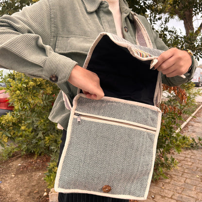 Person holding a patterned bag outdoors with greenery in the background