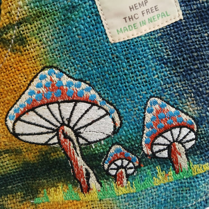 Embroidered mushrooms on a fabric background with a label indicating 'Hemp, THC Free, Made in Nepal'.