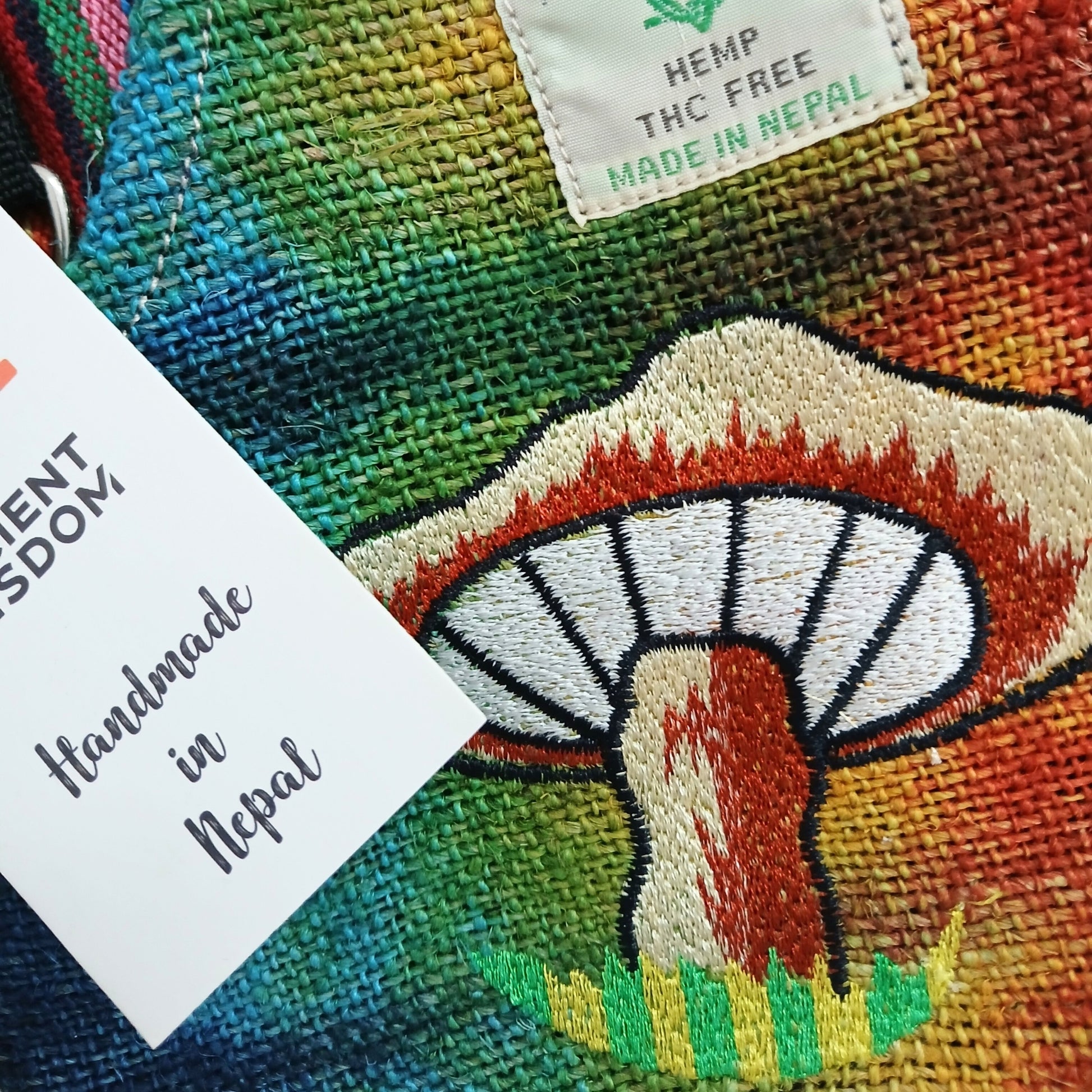 Colorful fabric with embroidered mushroom design and 'Hemp THC Free Made in Nepal' label.