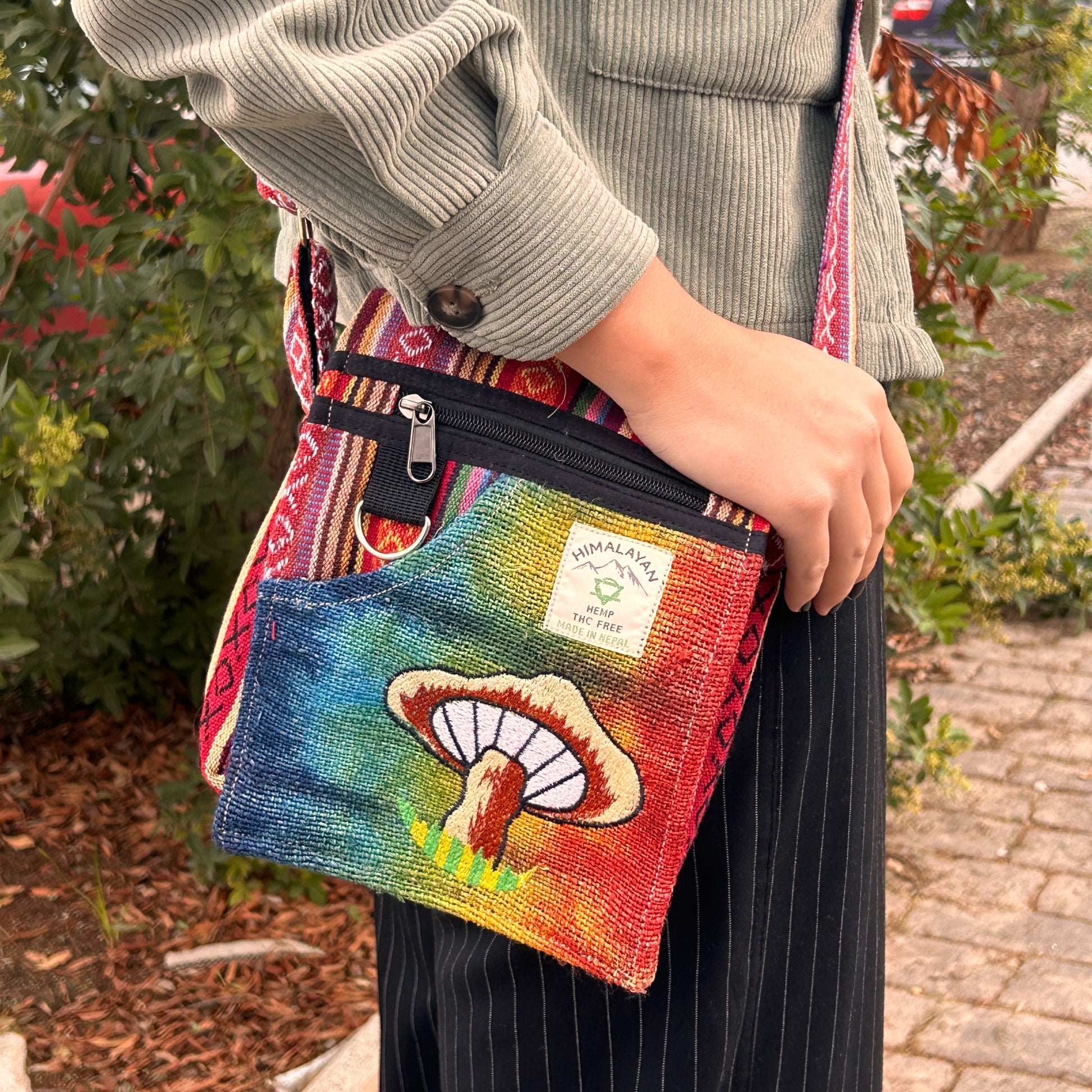 Person holding a colorful bag with a mushroom design outdoors