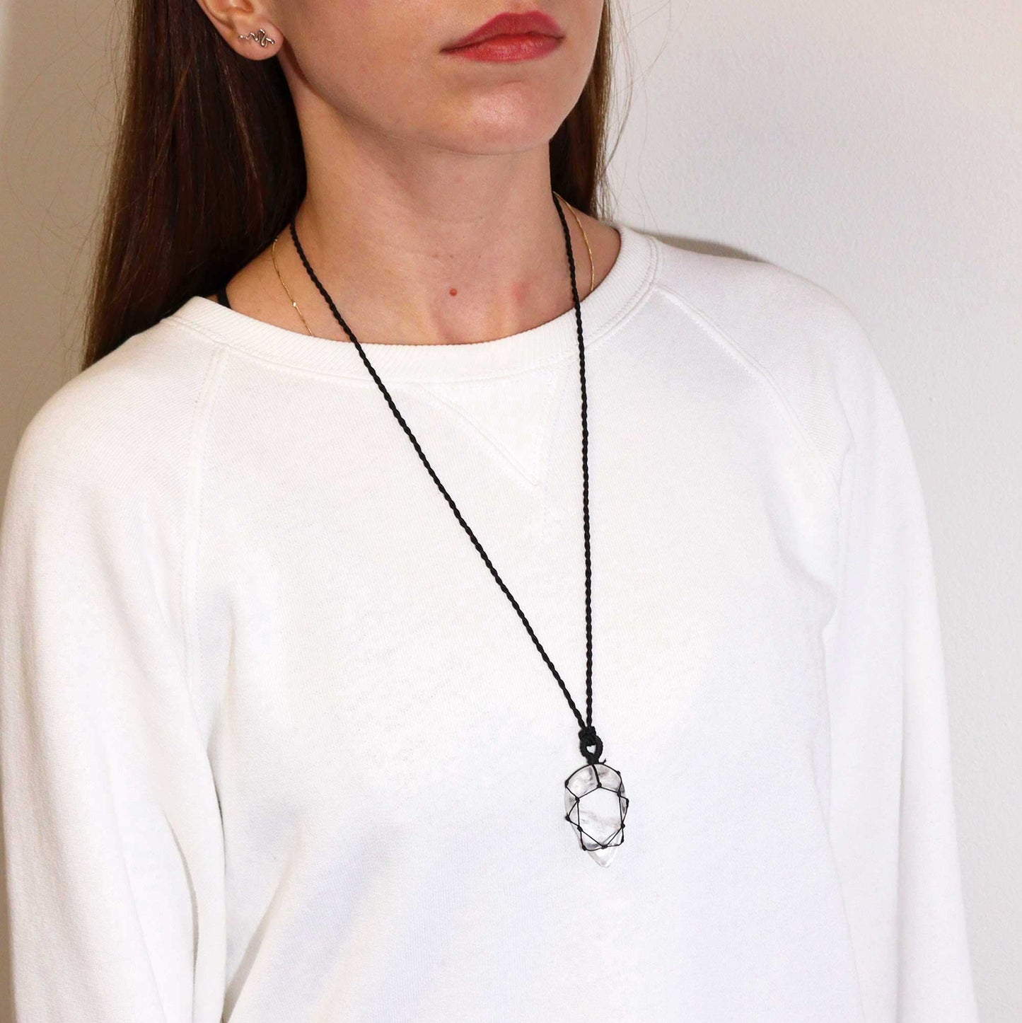 Woman wearing a black necklace with a Laced Gemstone Teardrop Pendant - Rock Quartz on a plain background