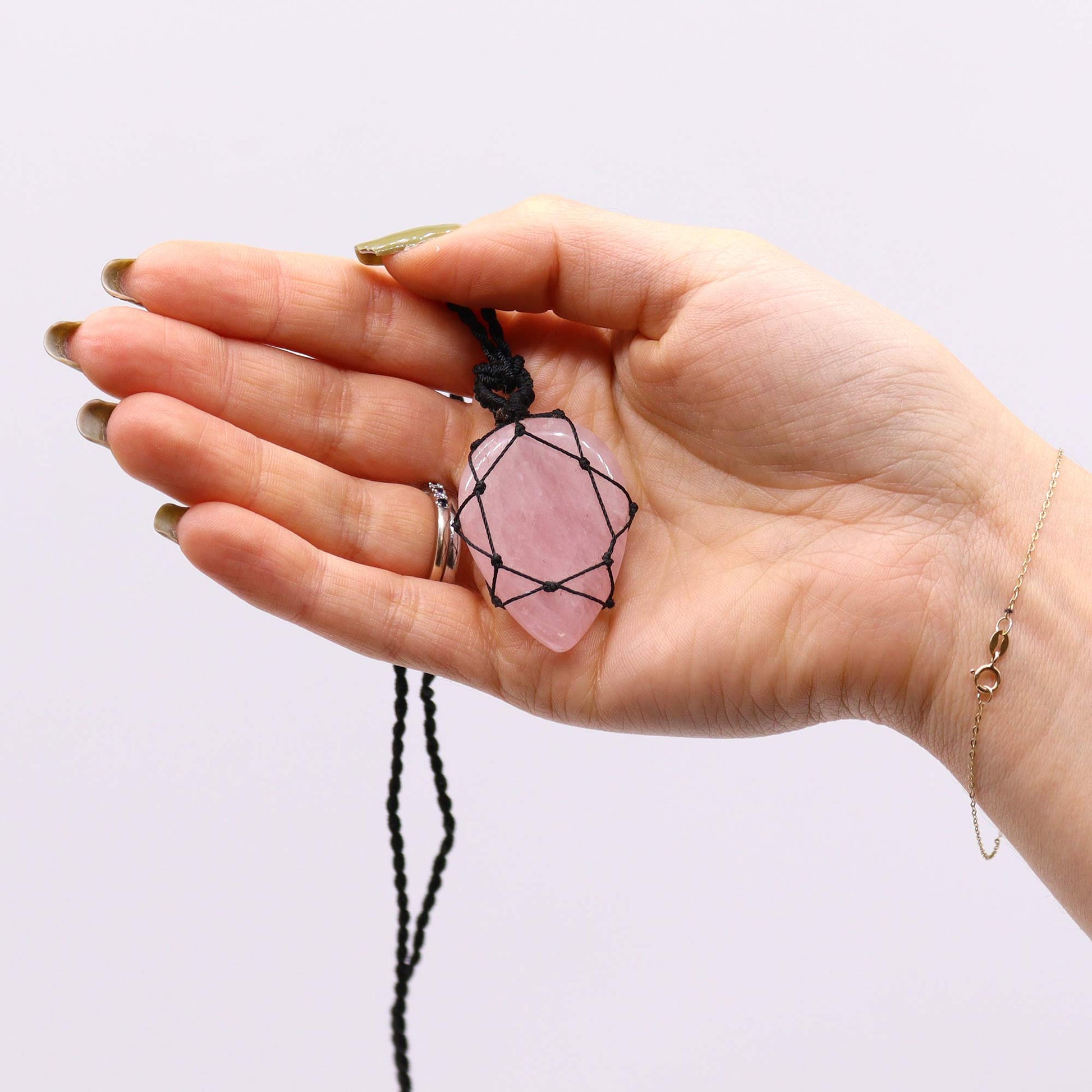 Hand holding a pink Laced Gemstone Teardrop Pendant - Rose Quartz against a white background