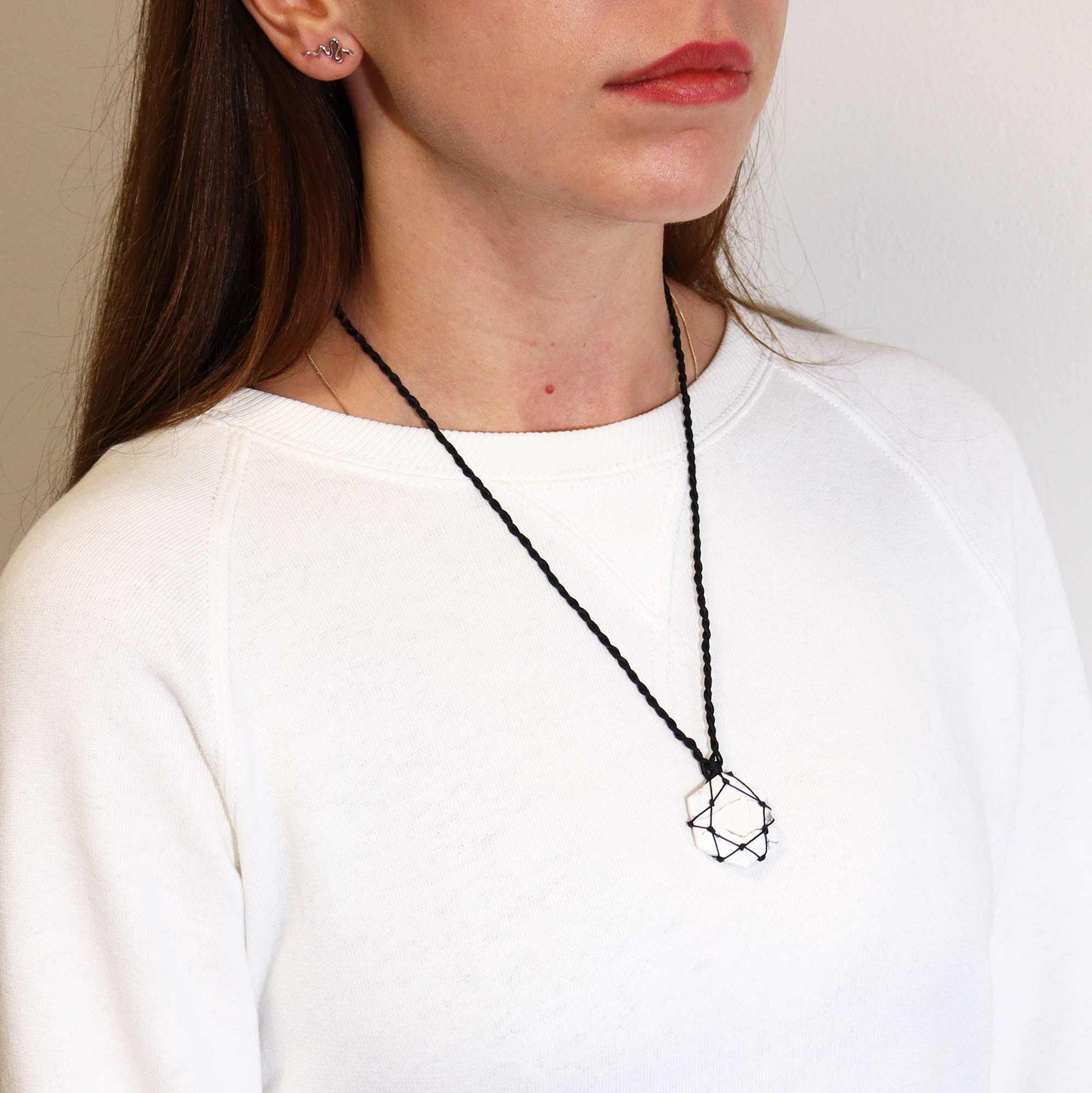 Person wearing a Laced Gemstone Hexagon Pendant - White Howlite necklace against a plain background
