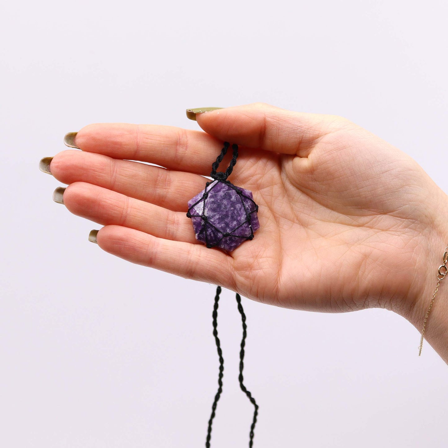 Hand holding a purple Laced Gemstone Hexagon Pendant - Lepidolite against a white background