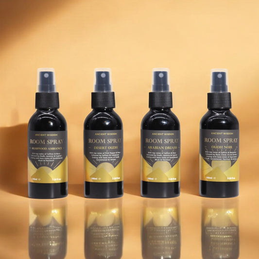 Four black spray bottles with labels, each labeled 'ROOM SPRAY' and different variant names, arranged in a row against a beige background.