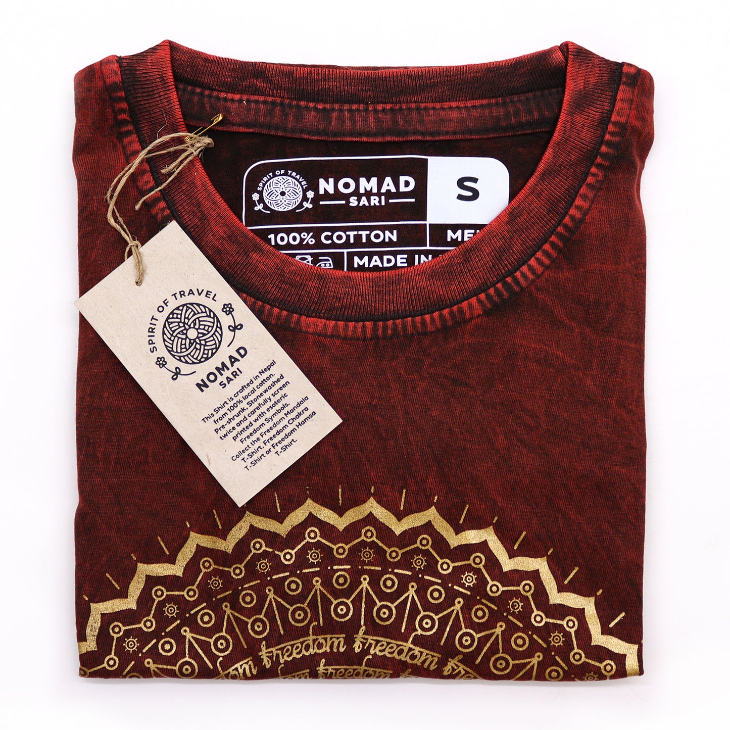 Folded maroon t-shirt with gold embroidery and 'Nomad Sari' label on a white background