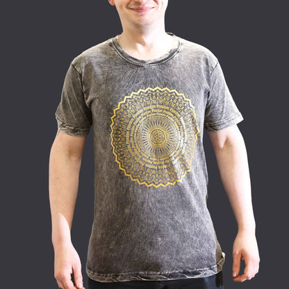 Person wearing a gray t-shirt with a gold mandala design on a plain background