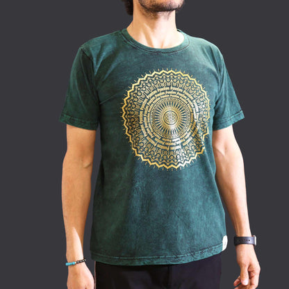 Person wearing a green t-shirt with a gold mandala design on a dark background