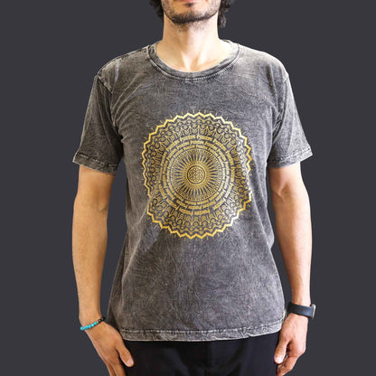 Person wearing a gray t-shirt with a gold mandala design on a dark background