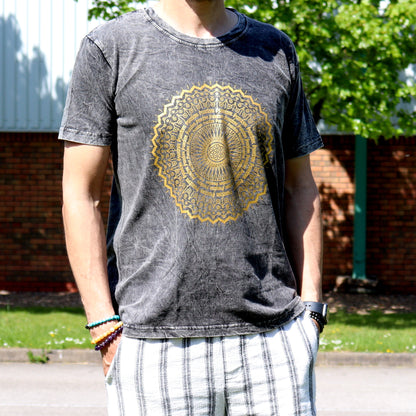 Person wearing a gray t-shirt with a gold mandala design outdoors.