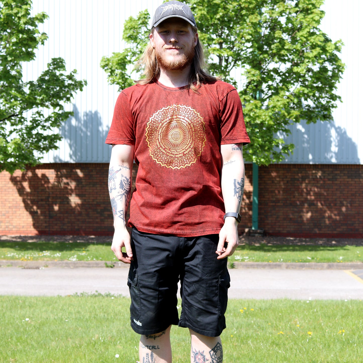 Man wearing a red t-shirt with a gold design outdoors