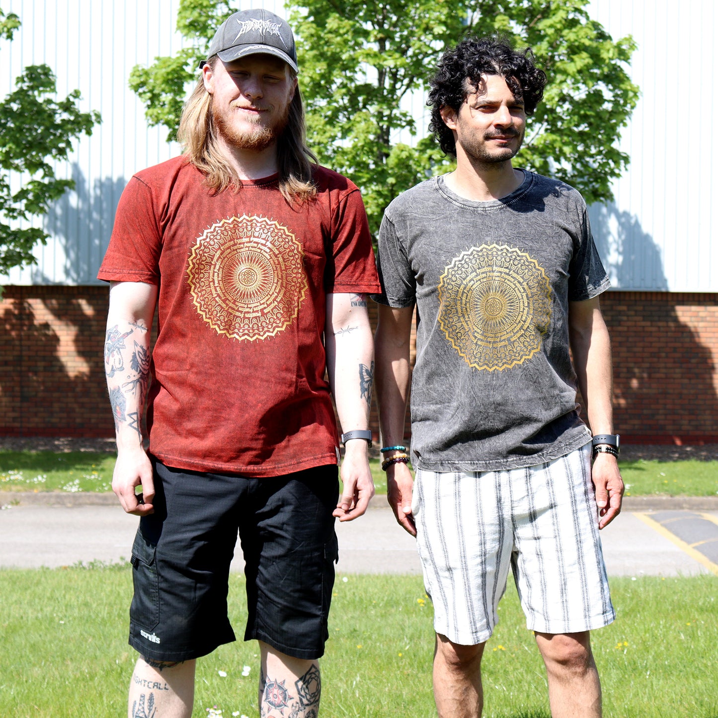 Two people wearing t-shirts with a gold mandala design outdoors.