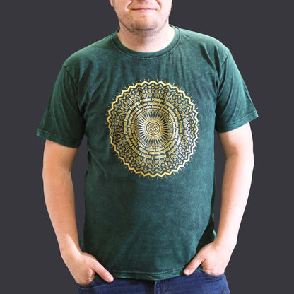 Person wearing a green t-shirt with a gold mandala design on a dark background