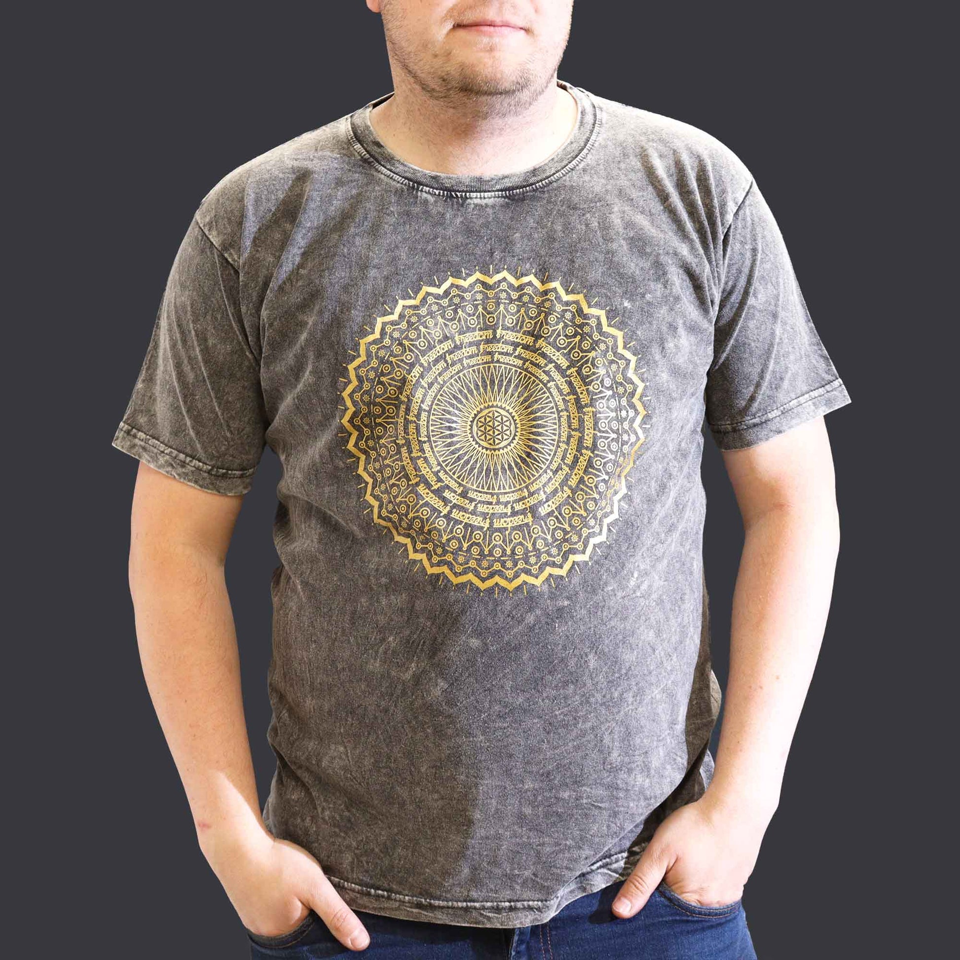 Person wearing a gray t-shirt with a gold mandala design on a plain background