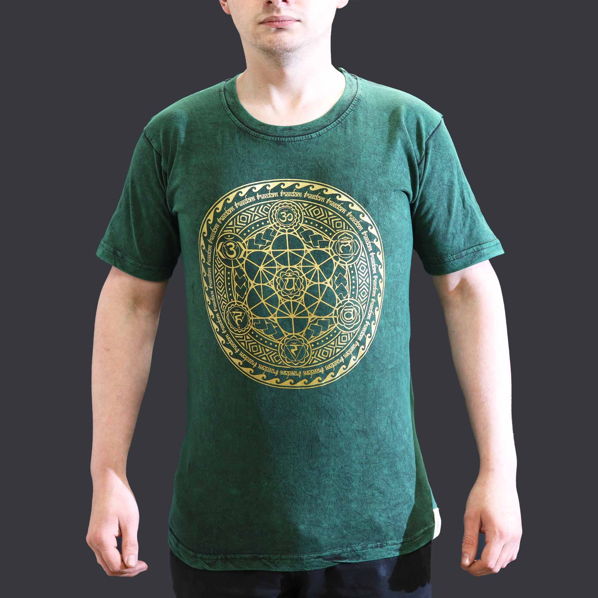 Green t-shirt with gold geometric design worn by a person on a dark background