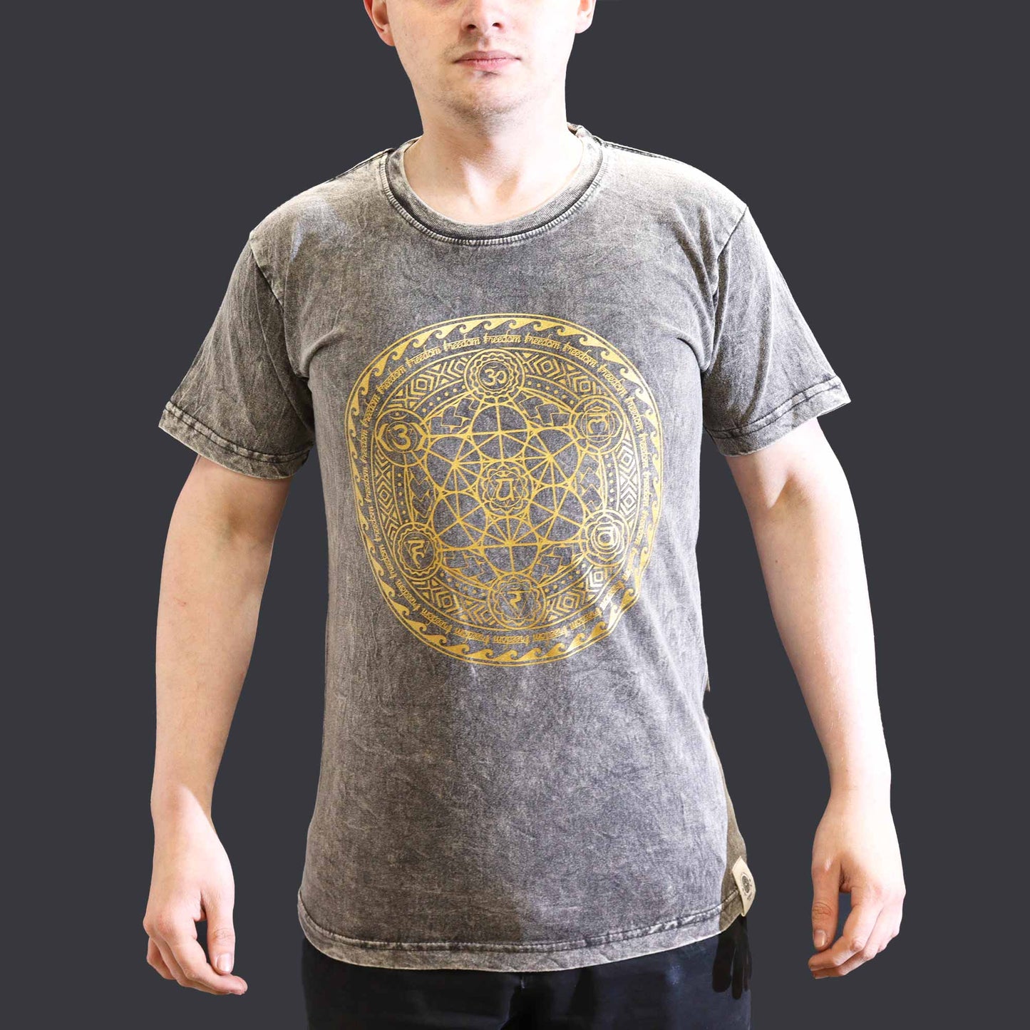 Front view of Person wearing a gray t-shirt with a gold geometric Chakra  design on a dark grey background