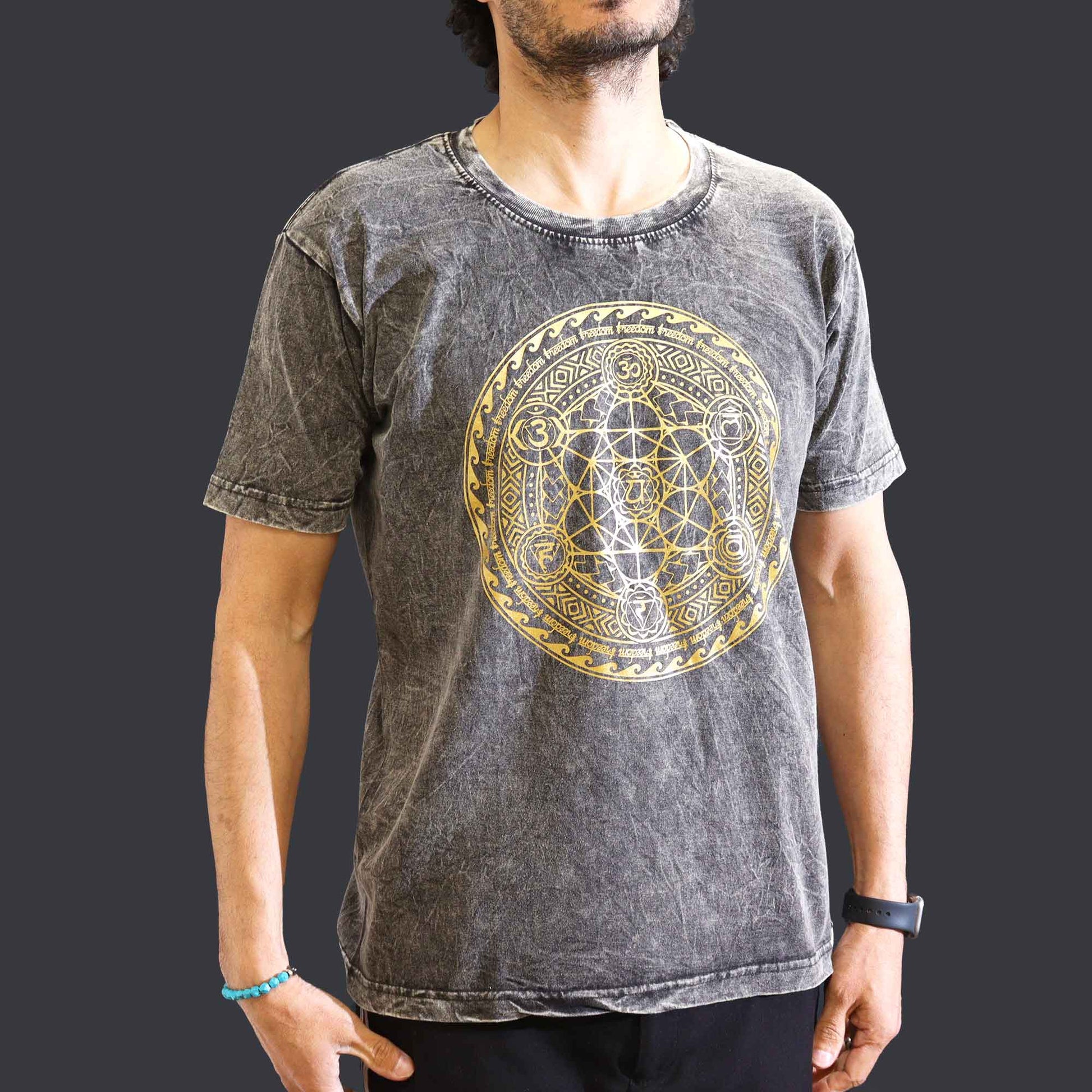 Person wearing a watch&  gray short sleeved t-shirt with a gold geometric Chakra  design on a dark background