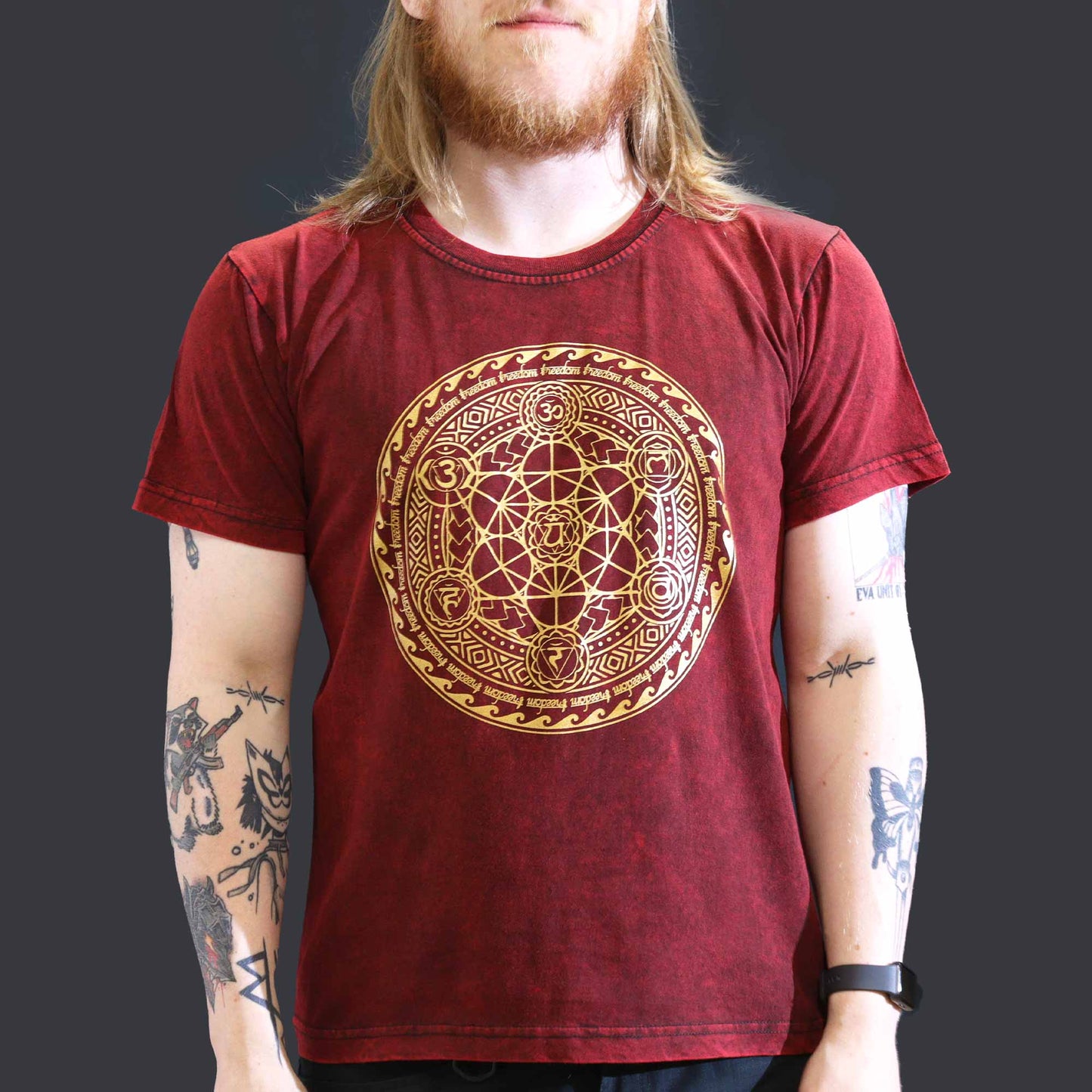 Person wearing a red t-shirt with a gold circular design on a dark background