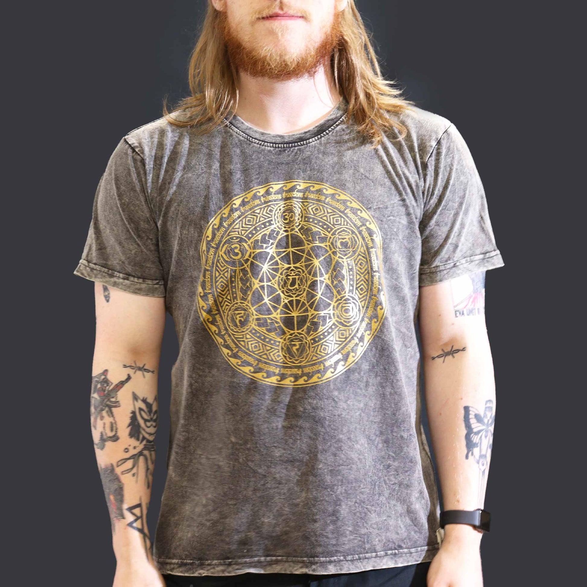 Person wearing a gray t-shirt with a gold geometric design on a black background