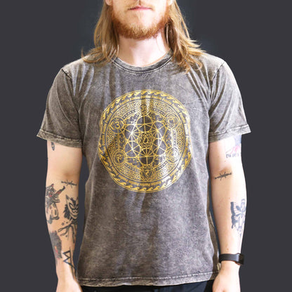 Person wearing a gray t-shirt with a gold geometric design on a black background