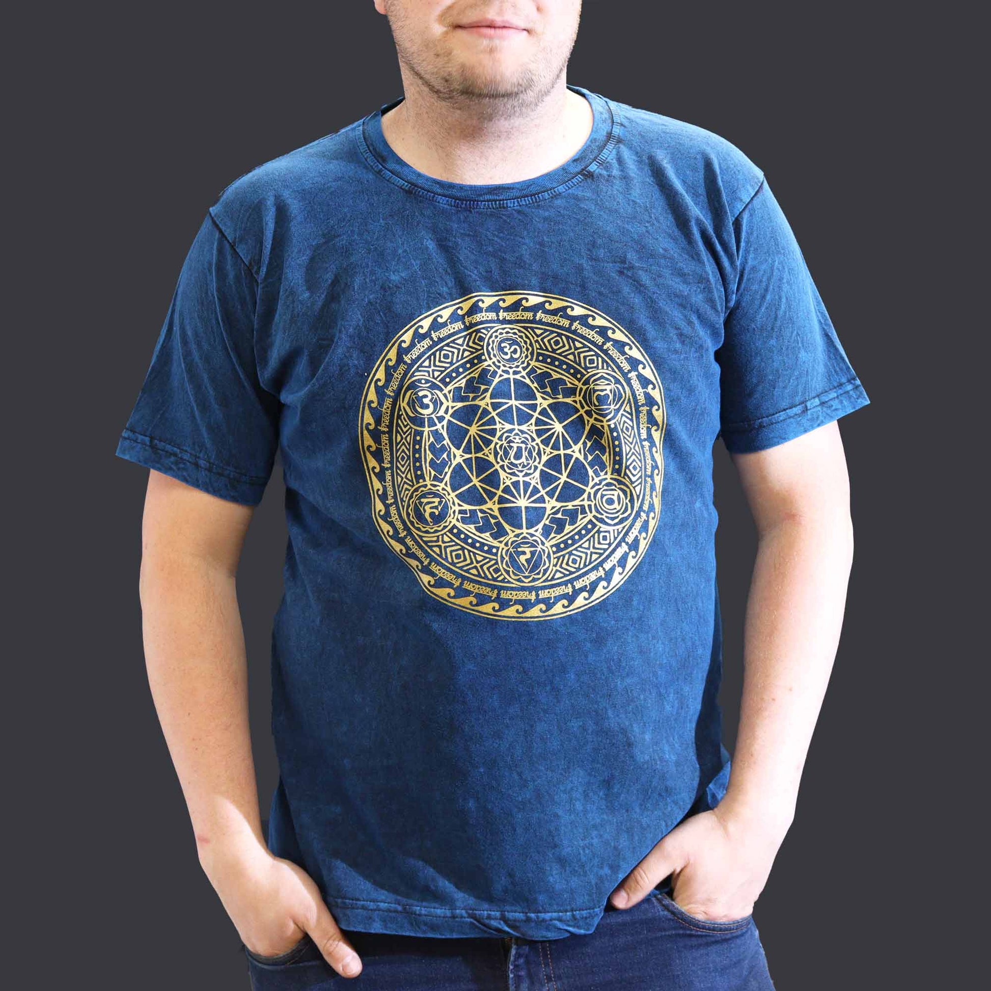 Person wearing a blue t-shirt with a gold geometric design on a dark background
