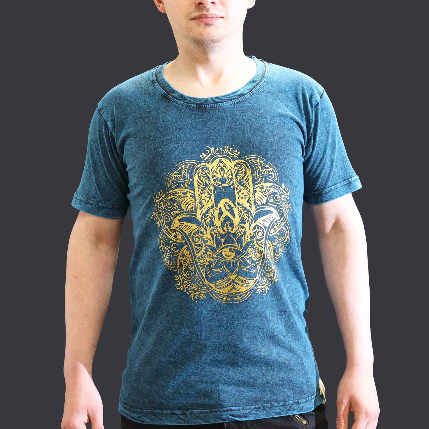 Person wearing a blue t-shirt with a yellow and black design on a dark background