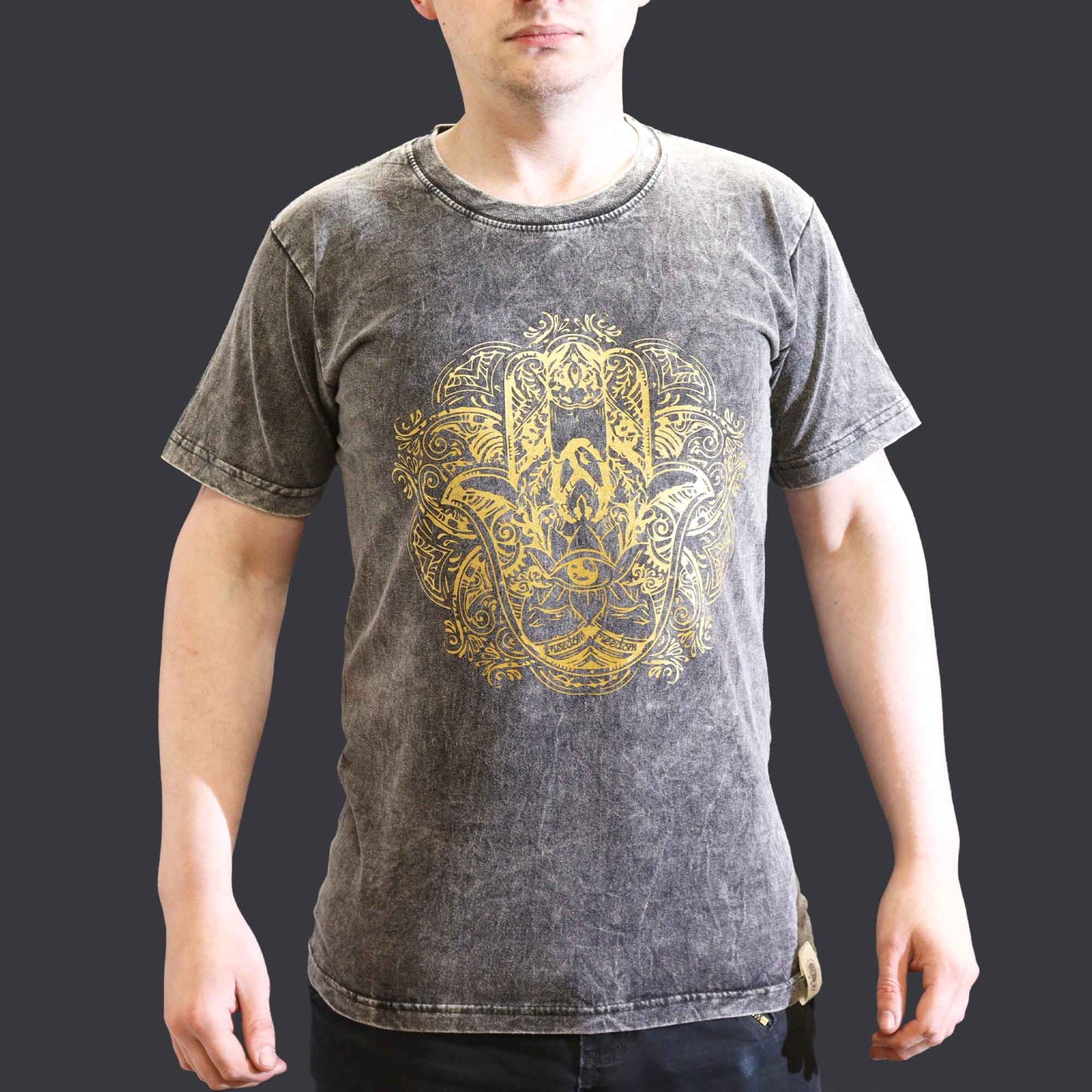 Person wearing a gray t-shirt with a yellow Hamsa graphic design on a dark background