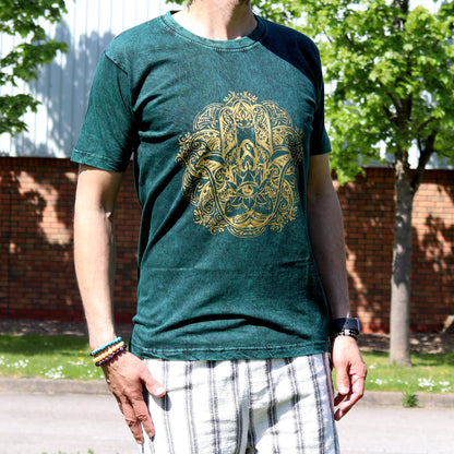 Person wearing a green t-shirt with a gold hamsa graphic design outdoors.