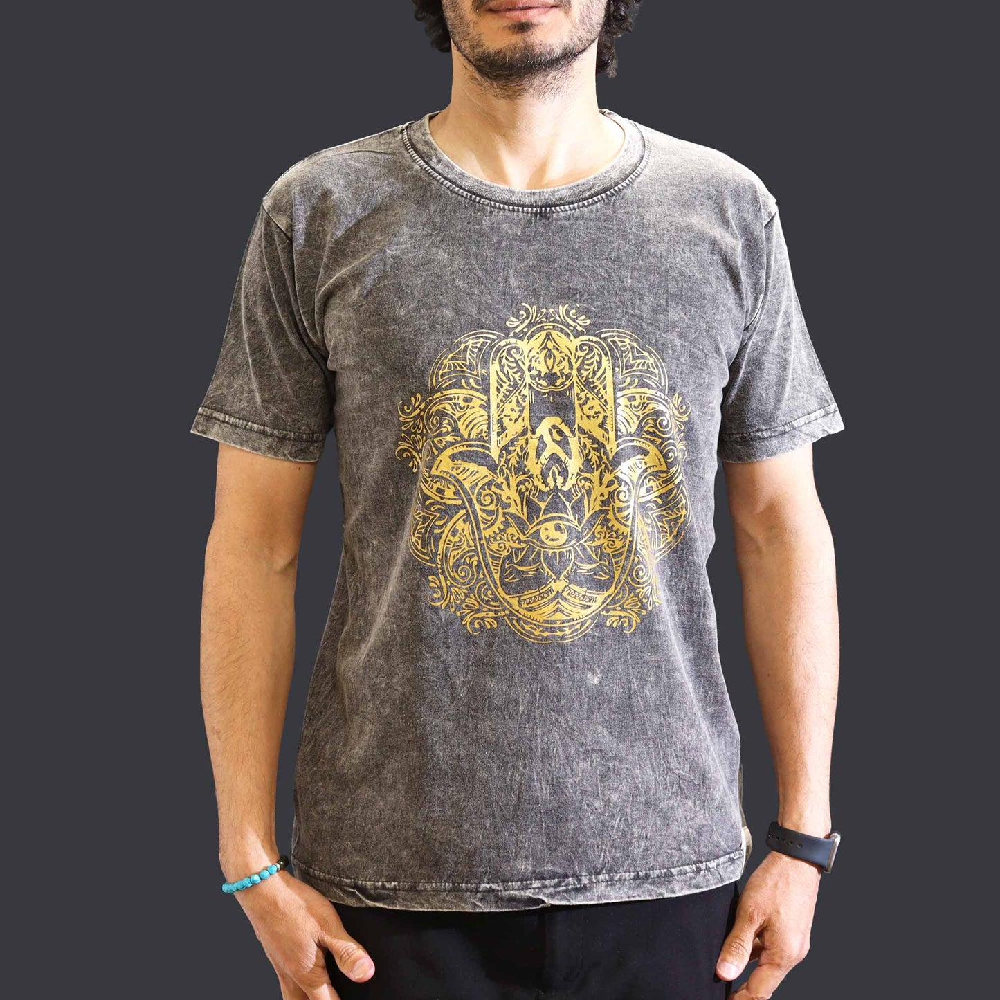 Person wearing a gray t-shirt with a yellow intricate Hamsa design on a plain background
