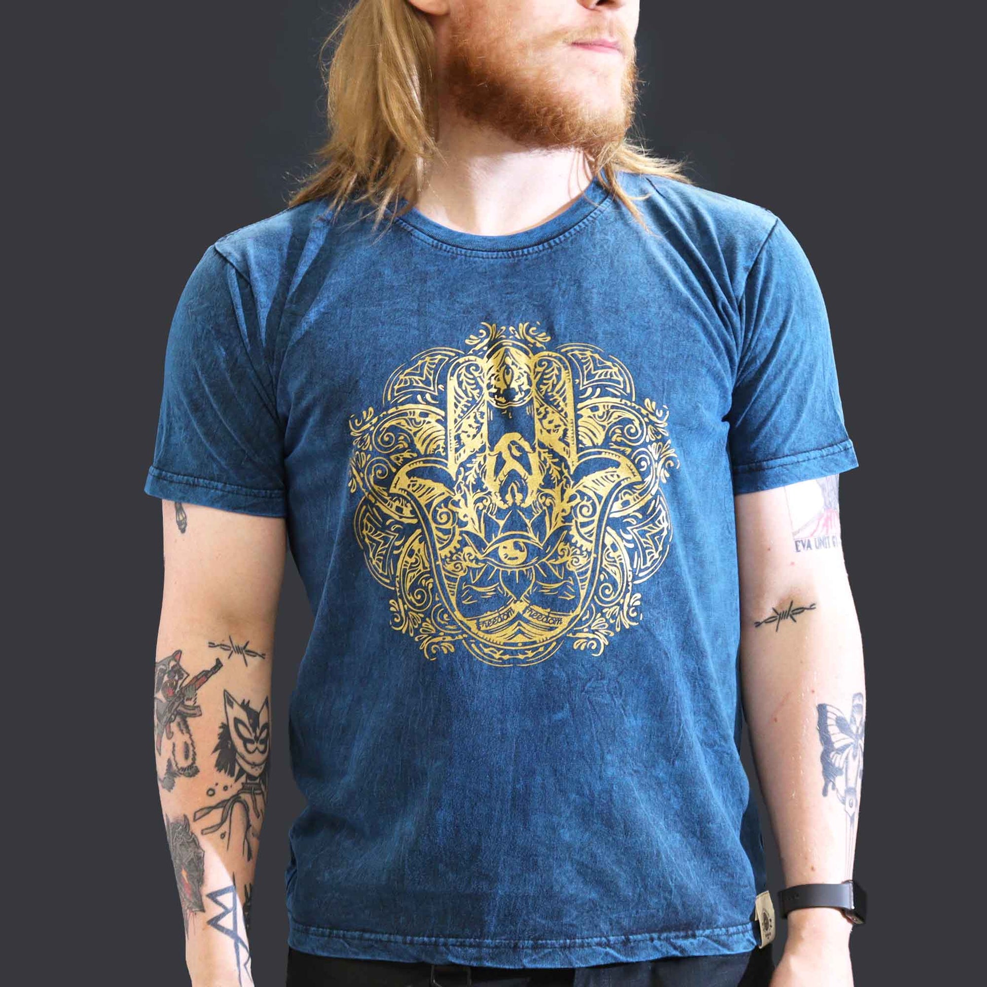 Person wearing a blue t-shirt with a gold Hamsa graphic design on a plain background