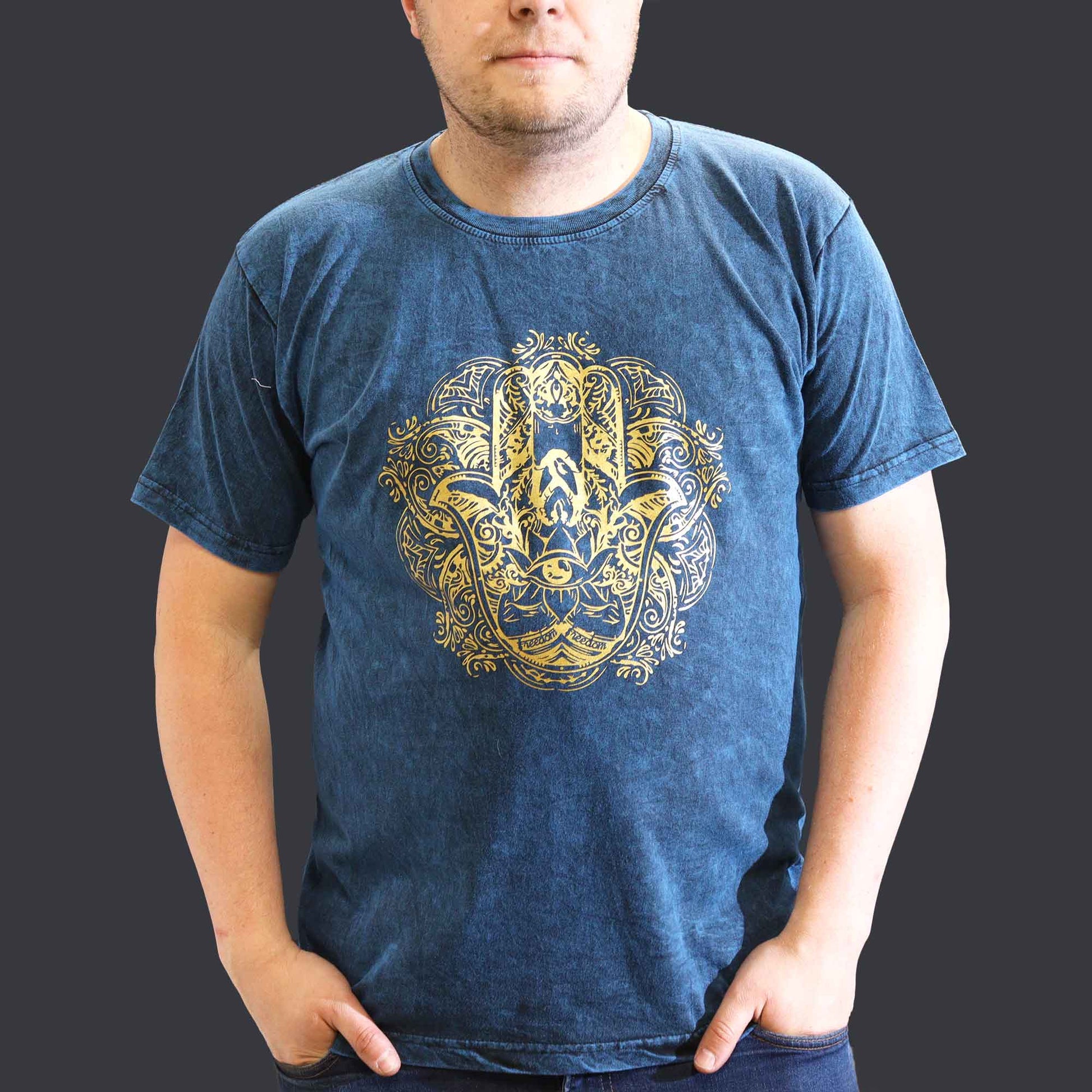 Person wearing a blue t-shirt with a gold Hamsa graphic design on a plain background