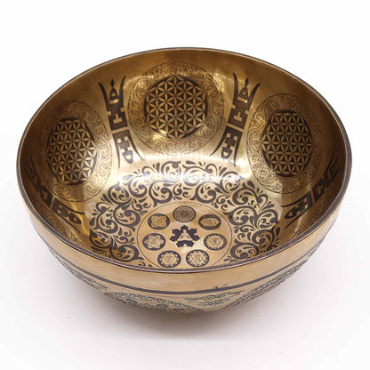 An engraved Tibetan singing bowl with intricate designs and symbols representing the 7 chakras, predominantly in a bronze or brown color. underground Allure Essex Uk