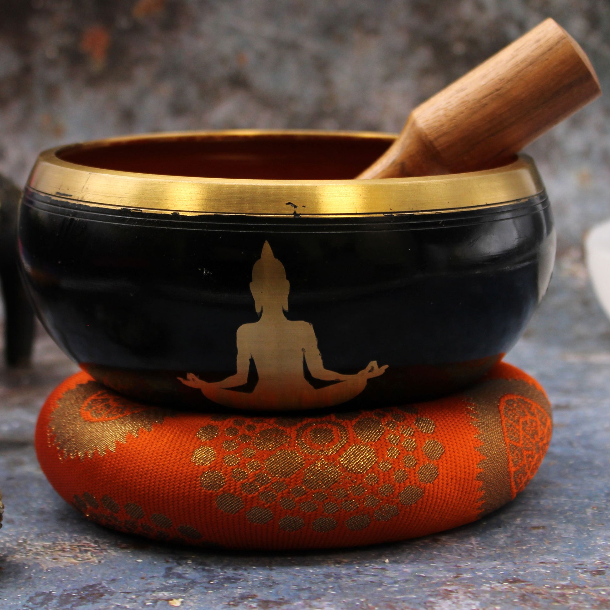 A singing bowl set including a blue and white singing bowl with a gold rim, a wooden mallet, and a black carrying bag, displayed on a white background.