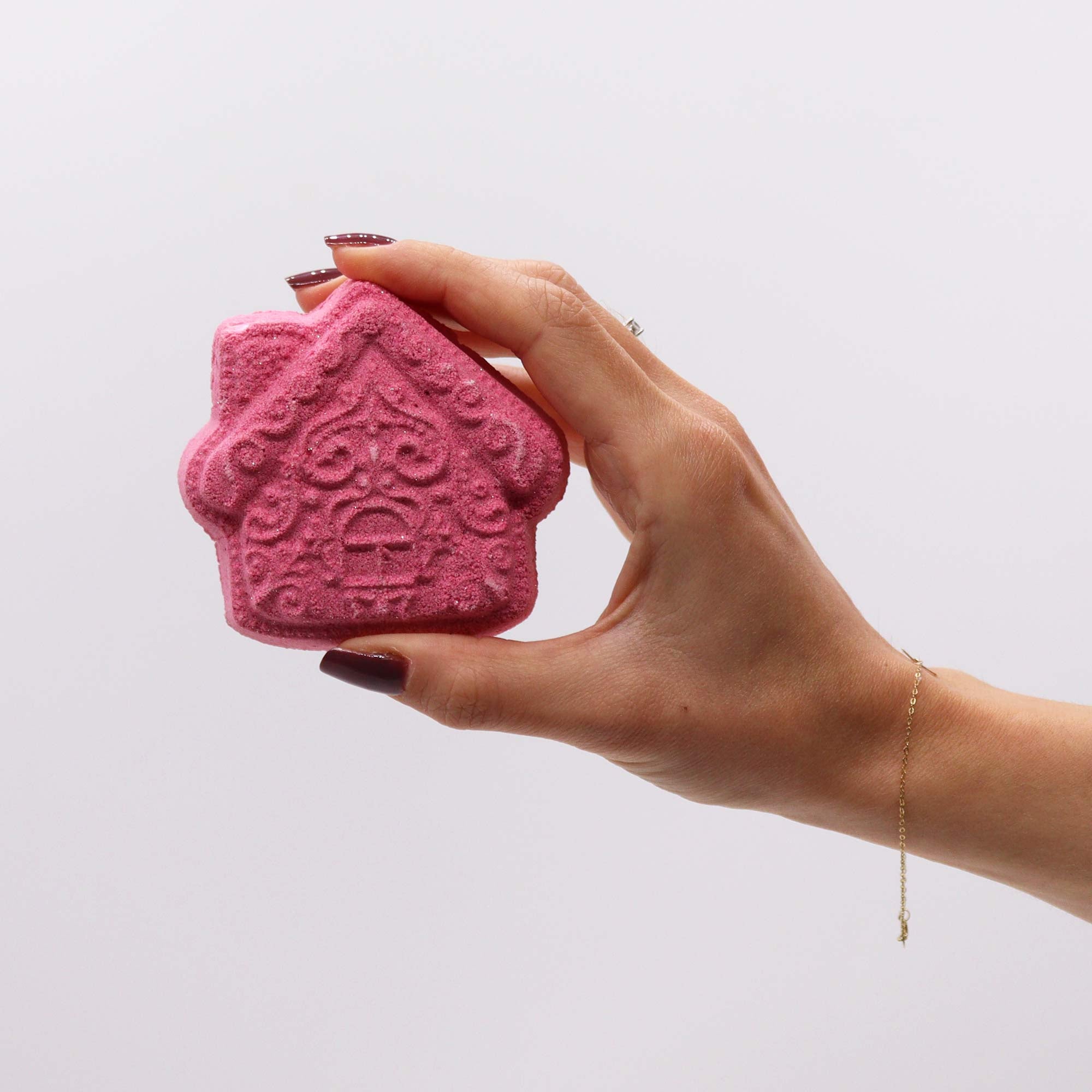 hand holding up a piece of red soap shaped as a house