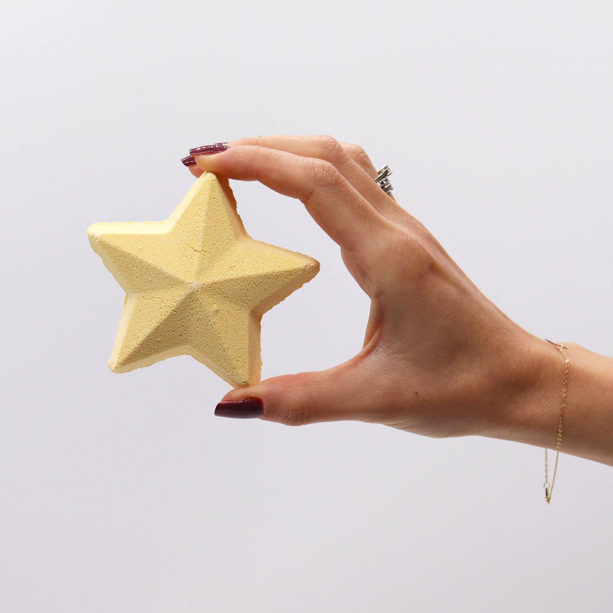 hand holding up a piece of yellow soap shaped as a star