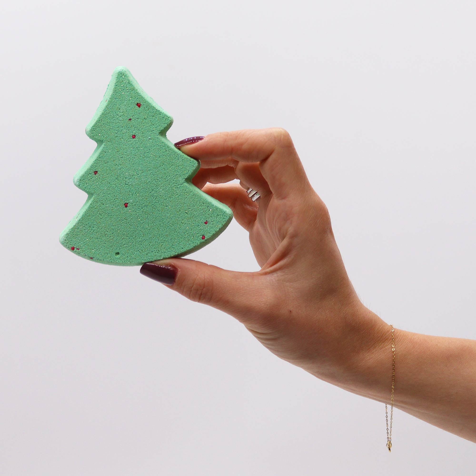 hand holding up a piece of green soap shaped as a tree