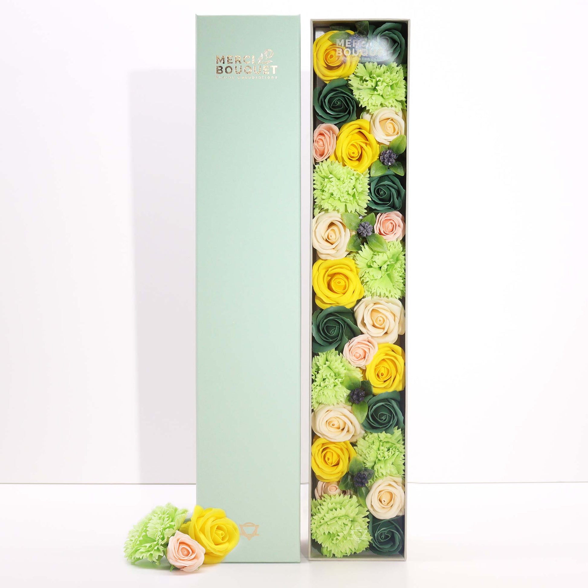 Floral arrangement in a box with a green box labeled 'Merci Bouquet' on a white background